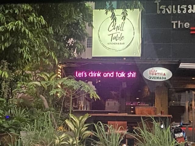 Restaurant storefront with neon signs and plants — Thailand 2023