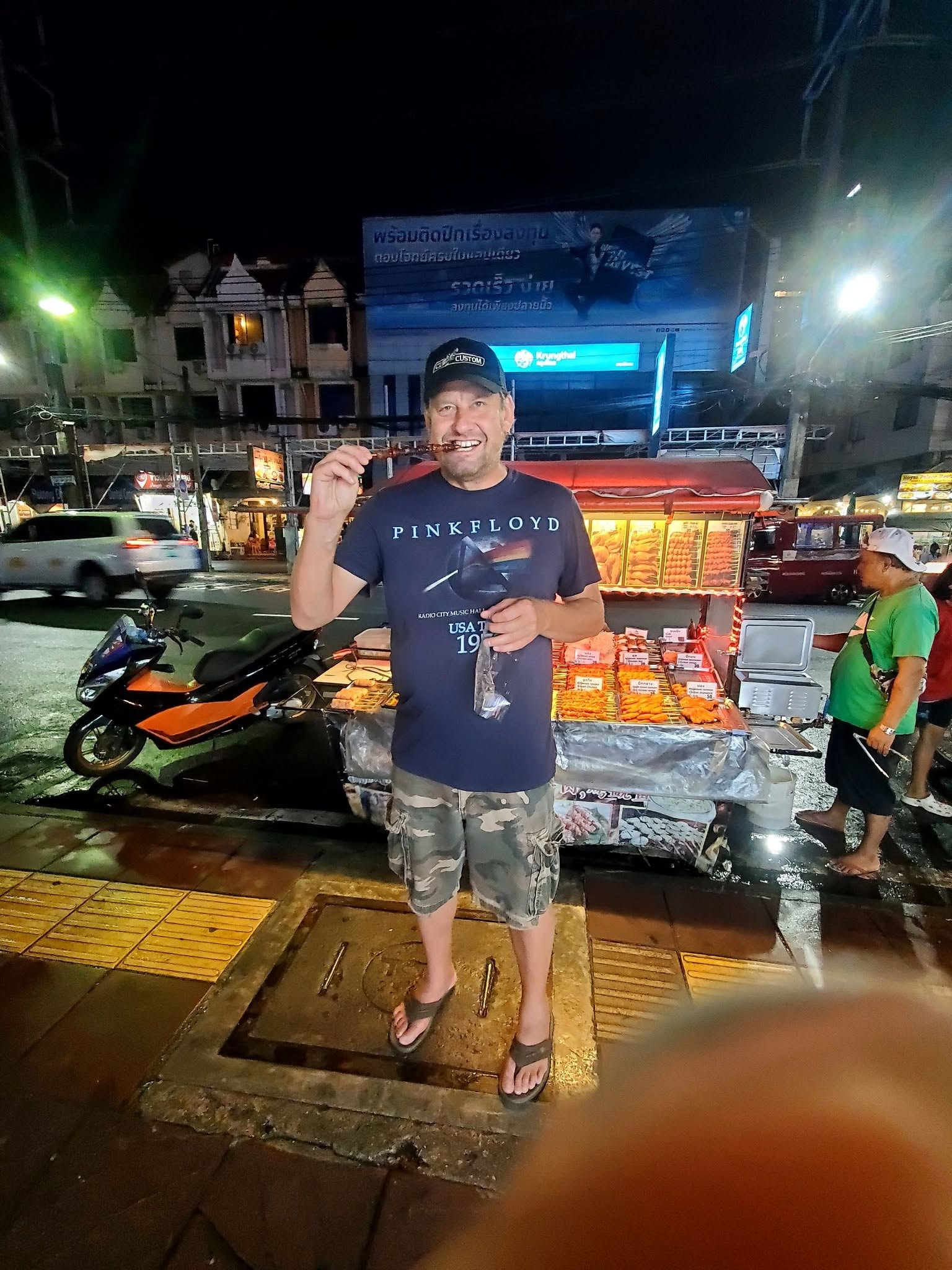 Brice eating street food skewers — Thailand night market