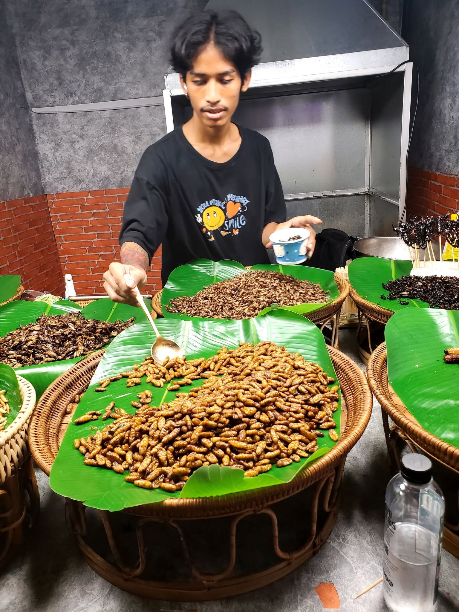 Vendor scooping roasted insects — Thailand